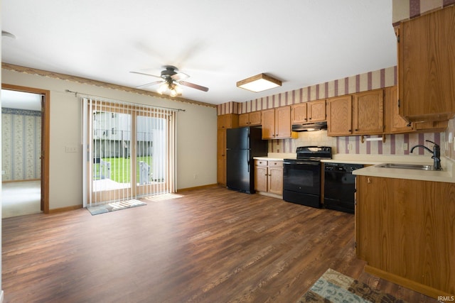 kitchen with under cabinet range hood, light countertops, black appliances, and a sink