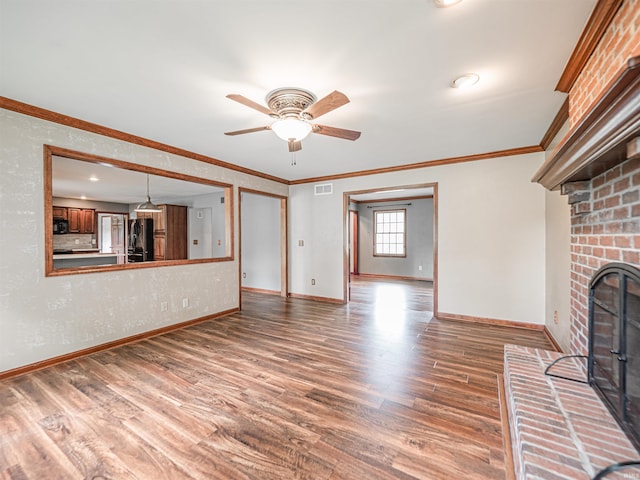 unfurnished living room with wood finished floors, ornamental molding, visible vents, a ceiling fan, and baseboards