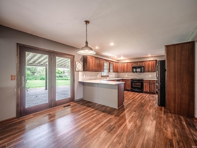 kitchen featuring a peninsula, dark wood-style flooring, light countertops, and black appliances