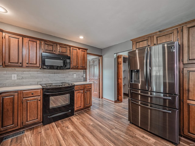 kitchen with tasteful backsplash, black appliances, visible vents, light countertops, and baseboards