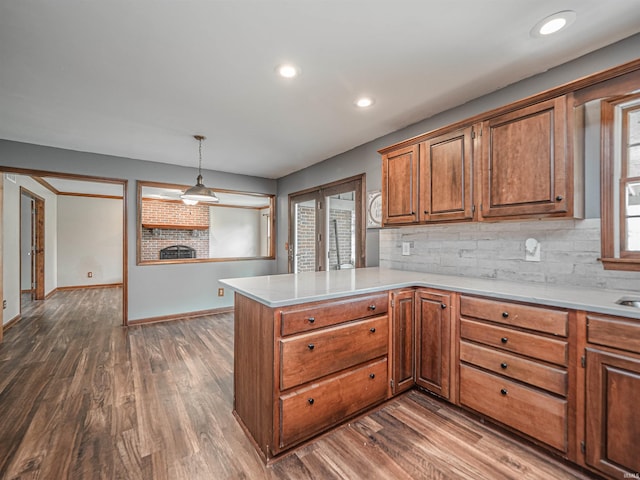 kitchen with backsplash, brown cabinets, a peninsula, and dark wood-style flooring
