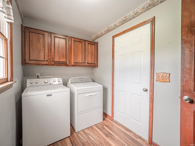 laundry area featuring washing machine and clothes dryer, light wood-style floors, and cabinet space