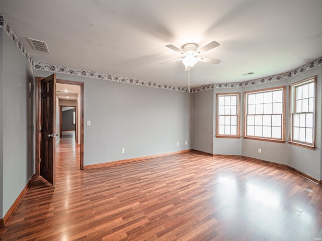 spare room with baseboards, ceiling fan, visible vents, and wood finished floors