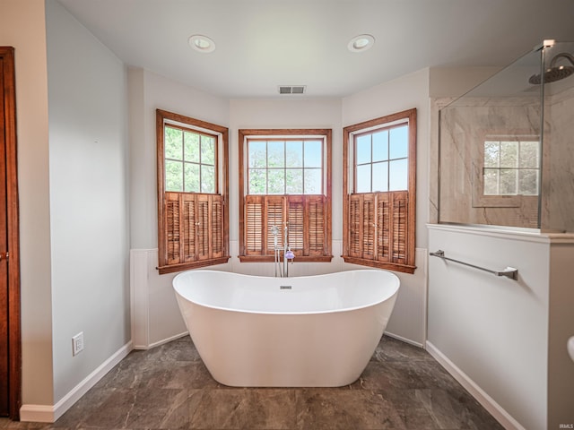 full bathroom featuring a stall shower, a freestanding bath, baseboards, and visible vents