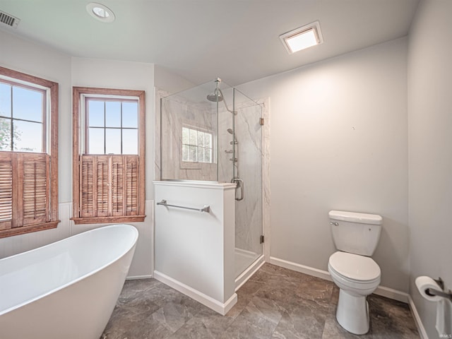 bathroom with a stall shower, a freestanding bath, toilet, and visible vents