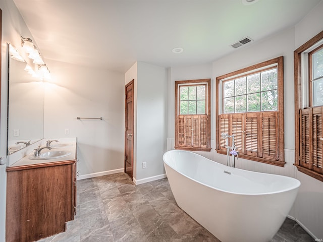 bathroom featuring a freestanding bath, baseboards, visible vents, and vanity