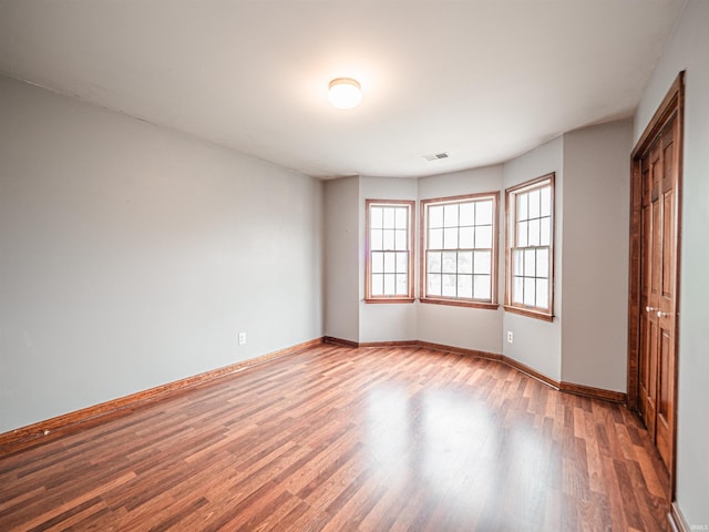 unfurnished room featuring baseboards, visible vents, and wood finished floors