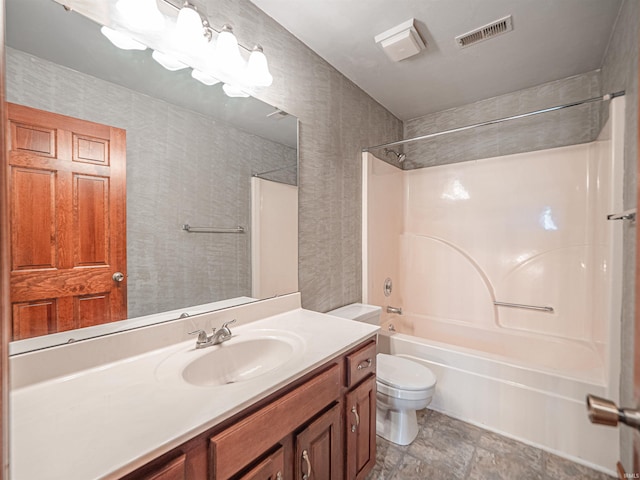 full bath with toilet, vanity, visible vents, stone finish flooring, and tub / shower combination