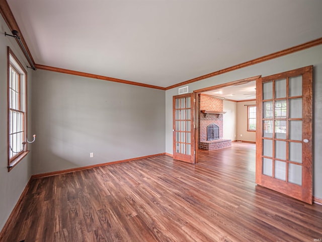 spare room featuring baseboards, visible vents, crown molding, wood finished floors, and a fireplace