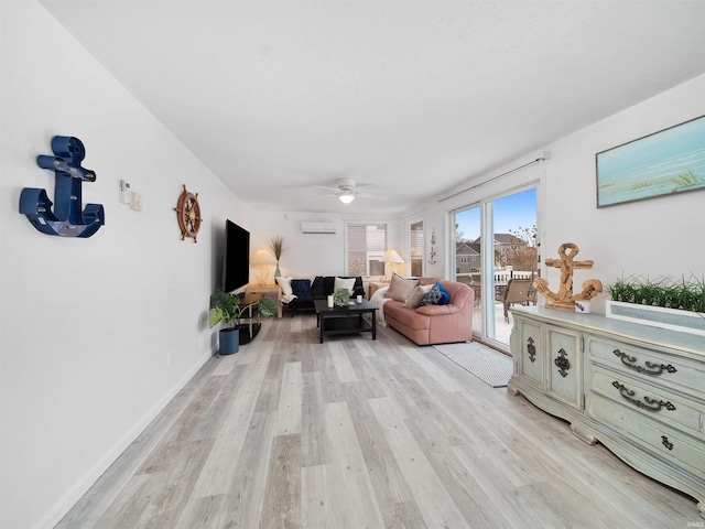 living area with light wood-style flooring, ceiling fan, and an AC wall unit