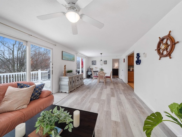 living room with light wood-type flooring, baseboards, and a ceiling fan