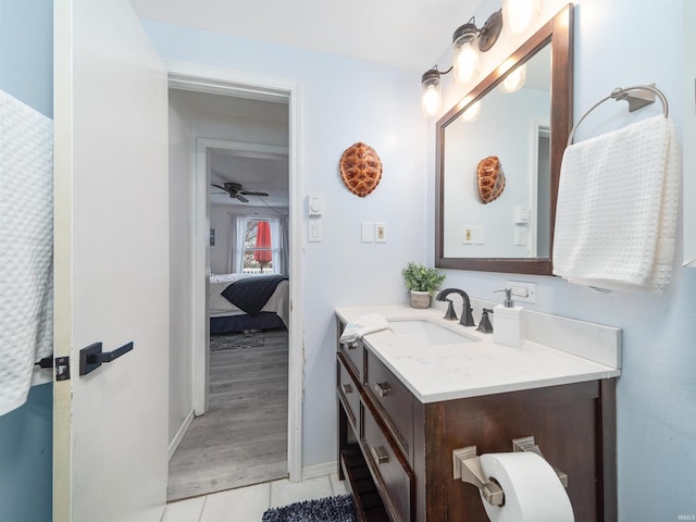 bathroom featuring tile patterned flooring, baseboards, ceiling fan, ensuite bath, and vanity