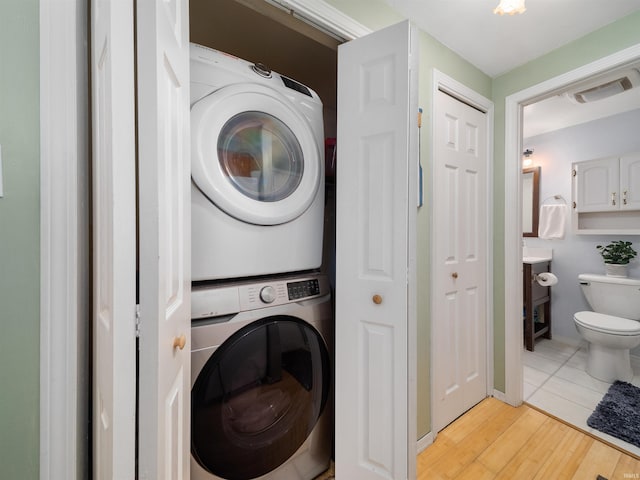 washroom featuring laundry area, stacked washing maching and dryer, visible vents, and light wood-style floors