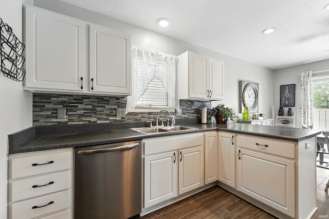 kitchen featuring a sink, a peninsula, tasteful backsplash, dishwasher, and dark countertops