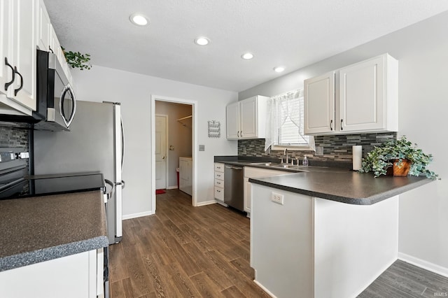 kitchen featuring a peninsula, dark countertops, stainless steel appliances, backsplash, and dark wood-style floors
