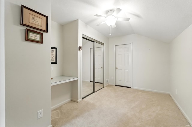 unfurnished bedroom featuring vaulted ceiling, light carpet, baseboards, and a ceiling fan