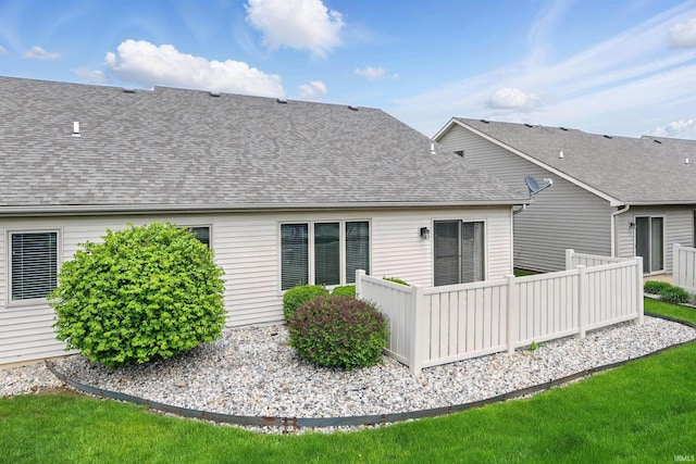back of property with a shingled roof and fence