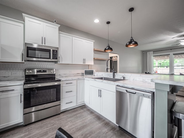 kitchen with a peninsula, a sink, open shelves, stainless steel appliances, and white cabinets