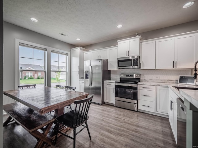 kitchen featuring recessed lighting, decorative backsplash, white cabinets, and appliances with stainless steel finishes