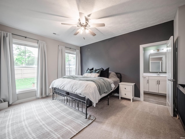 bedroom with visible vents, baseboards, a sink, and light carpet