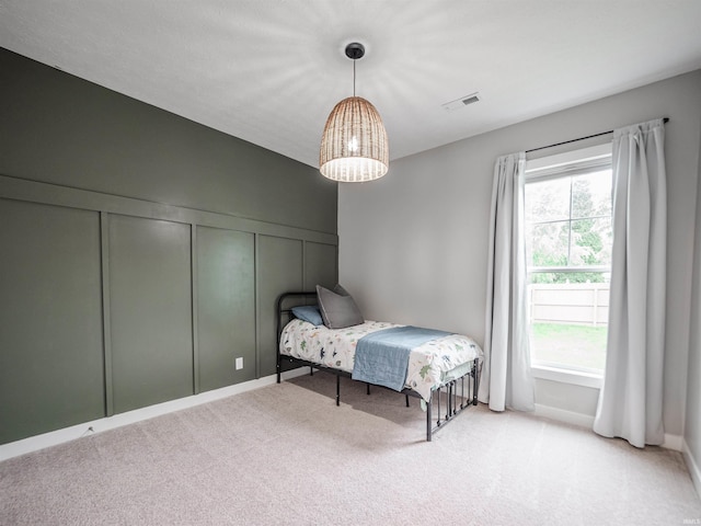 bedroom with carpet, visible vents, and a decorative wall