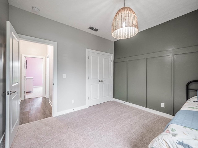 carpeted bedroom with a closet, visible vents, and a decorative wall