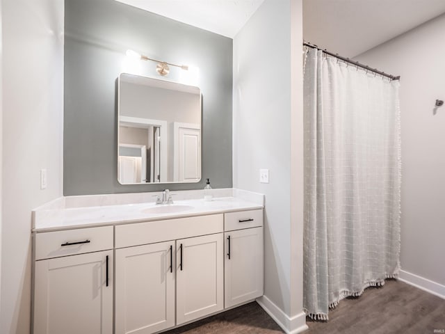 bathroom featuring vanity, curtained shower, baseboards, and wood finished floors