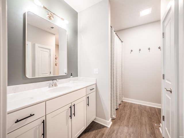 bathroom featuring baseboards, vanity, visible vents, and wood finished floors
