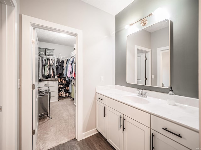 bathroom with a spacious closet, vanity, and wood finished floors