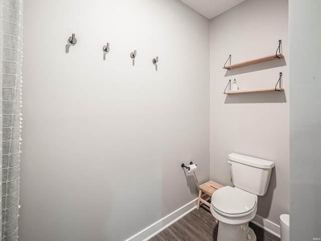 bathroom featuring toilet, wood finished floors, and baseboards