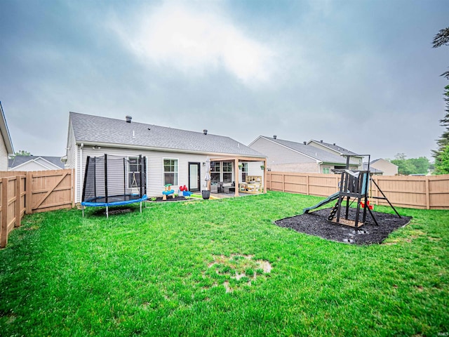 rear view of house with a fenced backyard, a trampoline, a patio, and a lawn