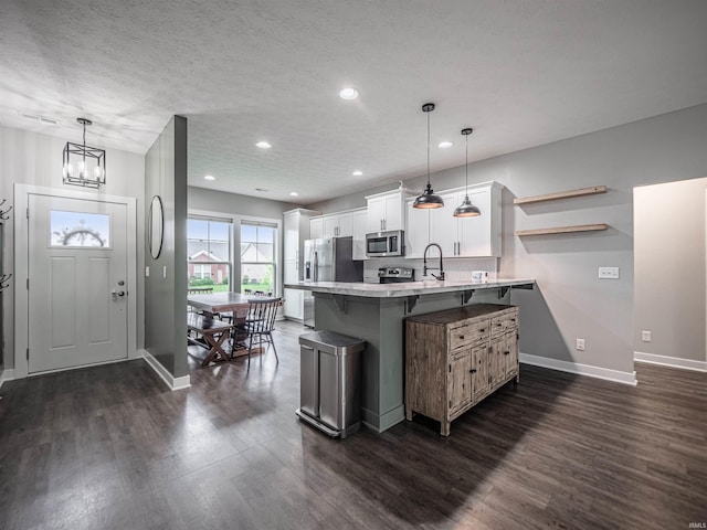 kitchen with a peninsula, a breakfast bar, stainless steel appliances, white cabinets, and light countertops