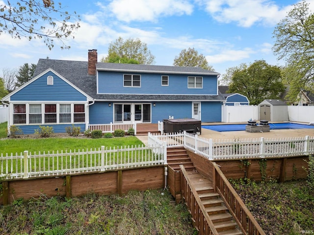 5259 E Willow Ct, Monticello, IN 47960 - rear view of property with a hot tub, a storage shed, a fenced backyard, a chimney, and a shingled roof