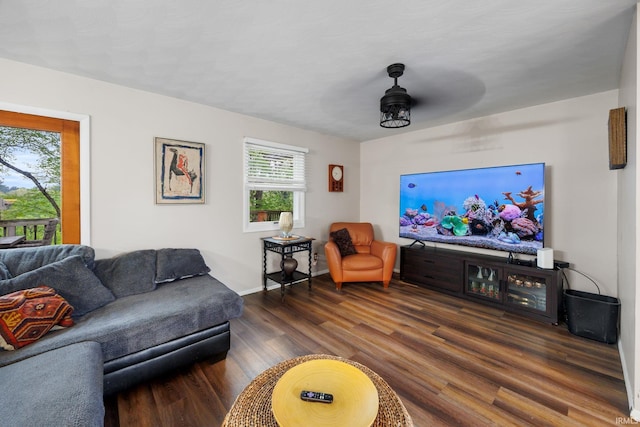 living area featuring baseboards, a ceiling fan, and dark wood-type flooring