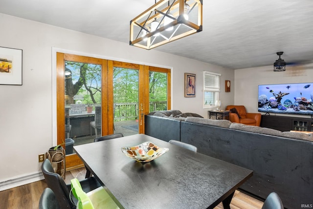dining space featuring wood finished floors, baseboards, and a baseboard heating unit