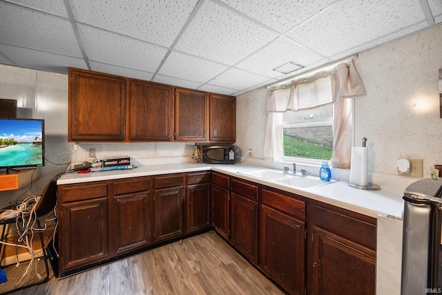 kitchen featuring a drop ceiling, light countertops, light wood-style flooring, and a sink