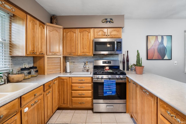 kitchen featuring light countertops, decorative backsplash, stainless steel appliances, and light tile patterned flooring