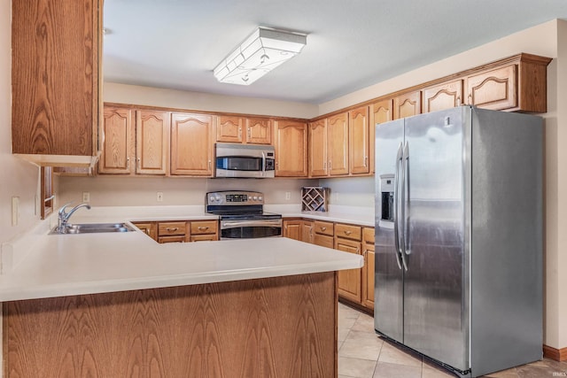 kitchen with a peninsula, light countertops, stainless steel appliances, and a sink