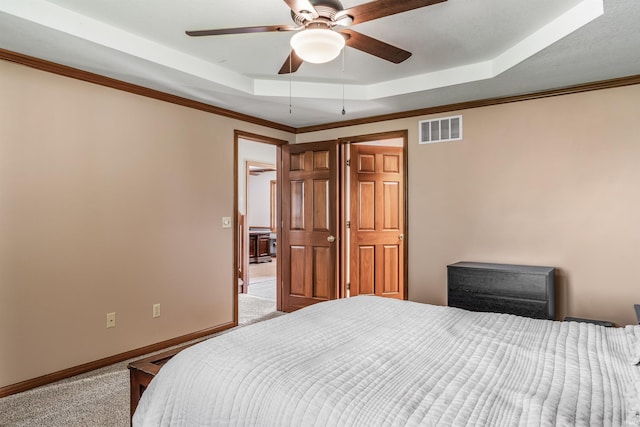carpeted bedroom featuring a ceiling fan, baseboards, a tray ceiling, and visible vents