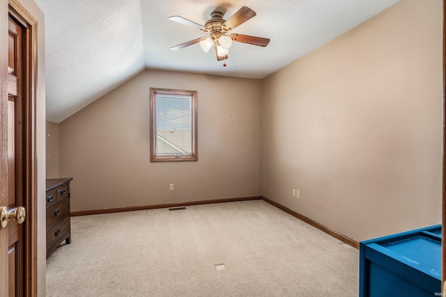 additional living space featuring visible vents, baseboards, ceiling fan, light carpet, and lofted ceiling