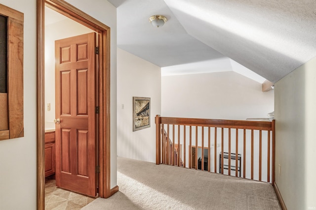 hall featuring an upstairs landing, carpet floors, and vaulted ceiling