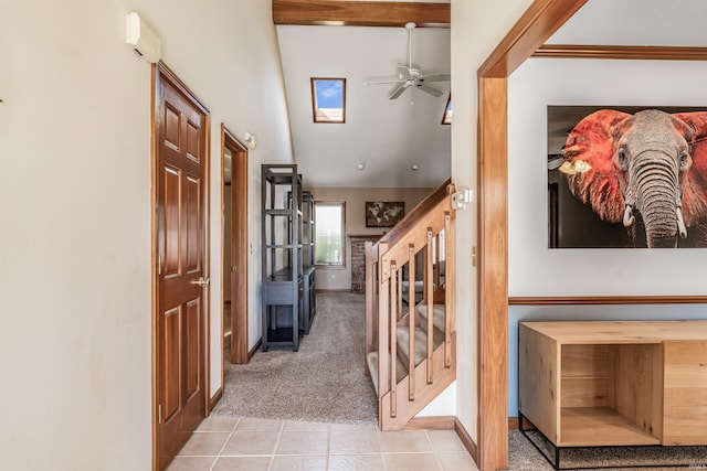 hall featuring carpet flooring, tile patterned floors, stairway, baseboards, and vaulted ceiling