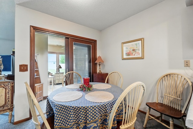 dining room with baseboards, a textured ceiling, and carpet floors