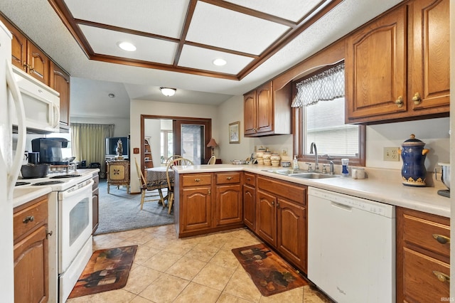 kitchen with a sink, white appliances, a wealth of natural light, and brown cabinets