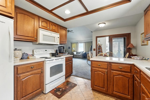 kitchen with brown cabinetry, light tile patterned floors, white appliances, light countertops, and light colored carpet