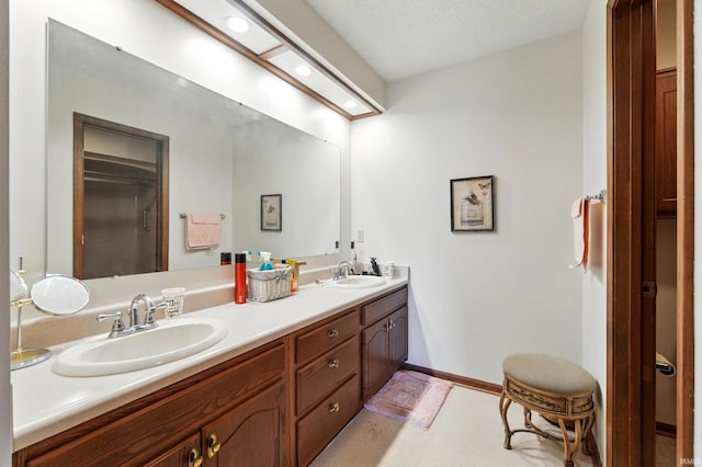 bathroom featuring recessed lighting, double vanity, baseboards, and a sink