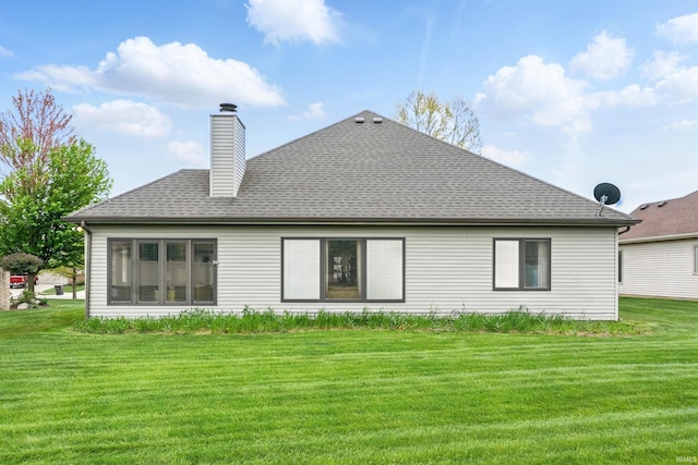 back of property featuring a yard, a shingled roof, and a chimney