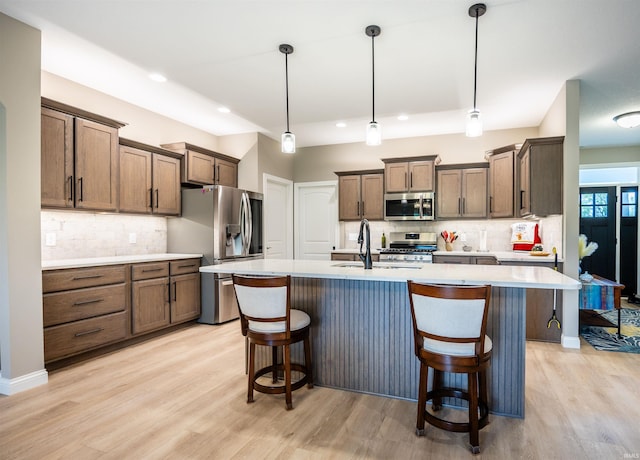 kitchen featuring light countertops, appliances with stainless steel finishes, decorative backsplash, and light wood-style floors