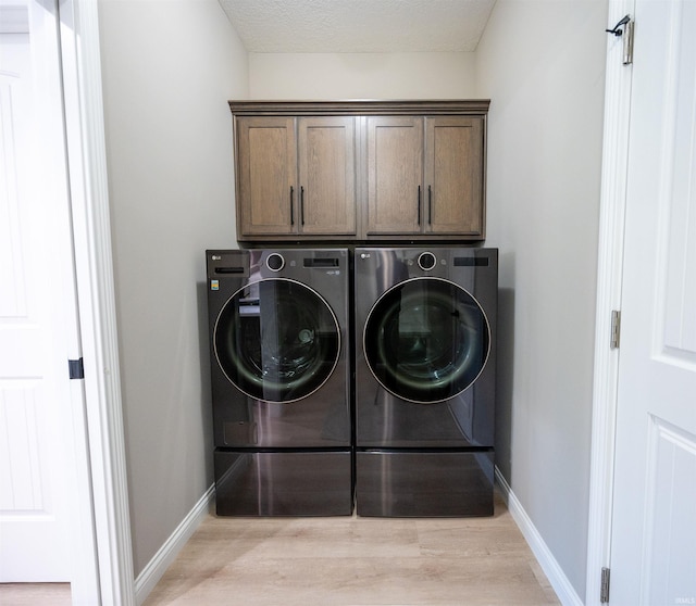 laundry room with washer and dryer, light wood finished floors, cabinet space, and baseboards