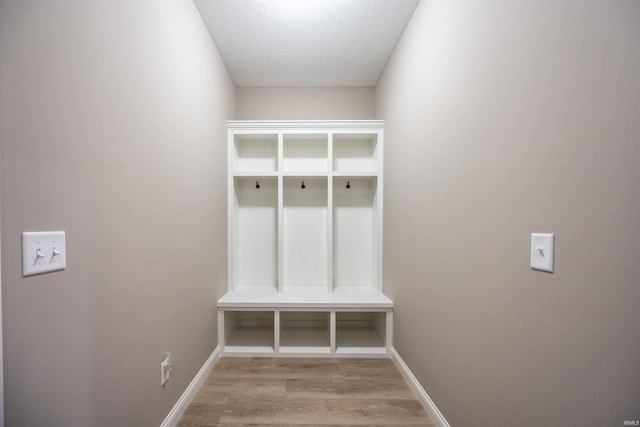 mudroom with a textured ceiling, wood finished floors, and baseboards